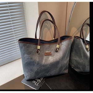 Detail of grey marble pattern tote bag with brown leather handles and fashion label