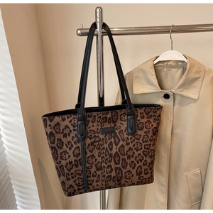 Close-up of leopard print tote bag with black leather brand logo and long handles