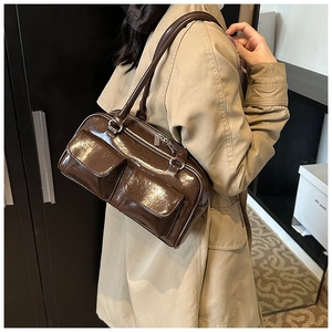 Détail du sac à bandoulière en cuir verni marron foncé brillant avec boucles argentées