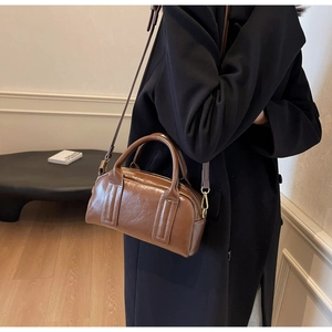 Detailansicht der dunkelbraunen glänzenden Boston-Tasche mit goldenem Reißverschluss