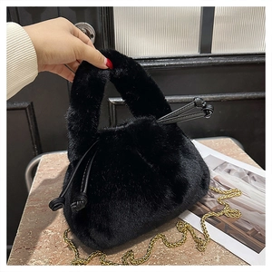 Detail of black faux fur bucket bag with golden chain strap and drawstring closure