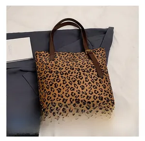 Detail of leopard print tote bag featuring brown leather straps and metal buckle accents