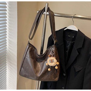 Detail of vintage brown tote bag with smooth texture and lion plush charm decoration