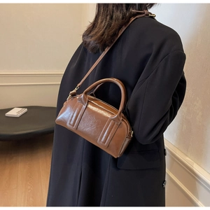 Borsa Boston vintage in pelle cerata marrone indossata a tracolla da una modella