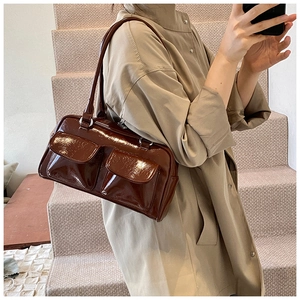 Détail du sac à main en cuir verni marron foncé avec deux poches à rabat et fini brillant