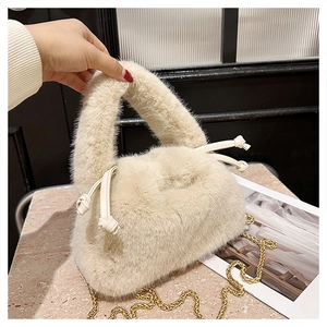 Detailed texture of plush cream bucket bag with leather drawstring and gold chain strap