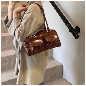 Détail du sac à bandoulière marron brillant avec deux poches avant et boucles argentées