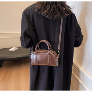 Retro braune Leder Boston Tasche kombiniert mit einem schlichten schwarzen Wollmantel