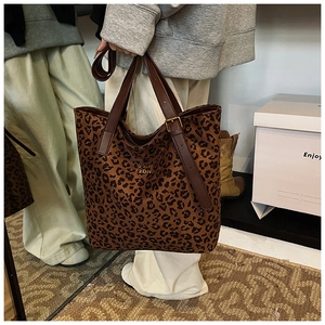Detail of leopard print tote bag with brown leather handles and gold metal hardware