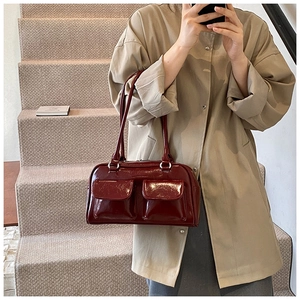 Détail du sac à main bordeaux en cuir verni avec deux poches avant et finition brillante