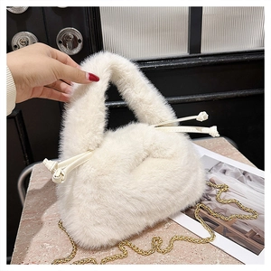 Detail of white faux fur bucket bag featuring golden chain and plush round handle