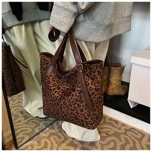 Detail of leopard print tote bag featuring gold lettering and premium leather handles