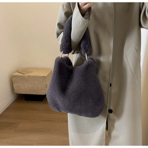 Détail d'un sac à main en peluche violet foncé avec des anneaux métalliques dorés sur l'anse