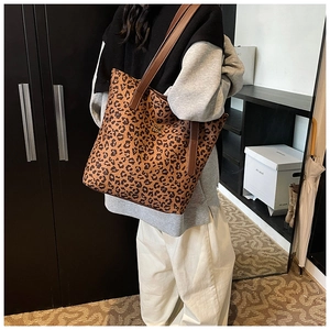 Detailed side view of leopard print tote bag with brown leather handles worn by a model