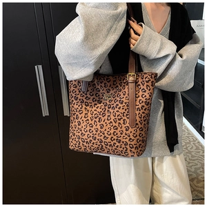 Detail of leopard print tote bag with brown leather handles and gold metal logo