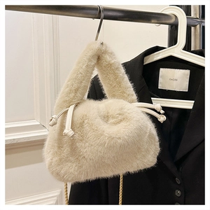 Detail of soft cream plush bucket bag featuring drawstring closure and gold chain strap