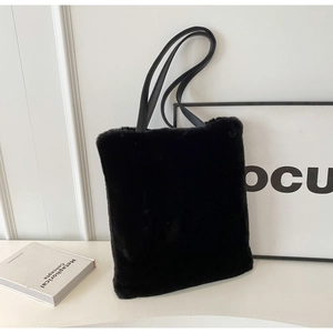 Détail de la texture d'un sac cabas en peluche noire avec des anses en similicuir résistant