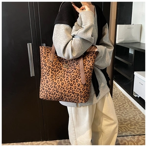 Detail of leopard print tote bag with gold metal logo and leather shoulder strap