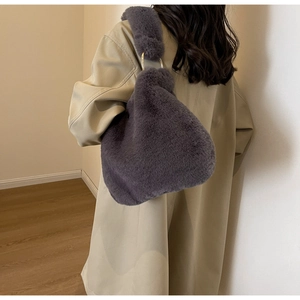Gros plan sur le sac en fausse fourrure violette avec anneau en métal doré sur la poignée