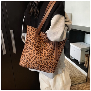 Detail shot of leopard print tote bag featuring a gold metal logo and brown leather handles