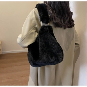 Détail du sac à bandoulière en fausse fourrure noire porté par un mannequin en manteau beige