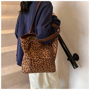 Detailed close-up of leopard print tote bag with brown leather handles and brand logo