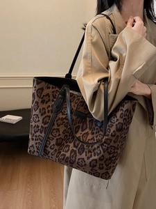 Fashionable leopard print large tote bag with black leather straps on beige trench coat