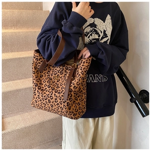 Detail of leopard print tote bag with brown leather straps and gold metal logo plaque