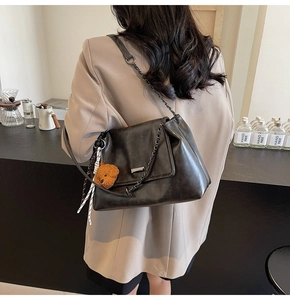 Détail d'un sac à bandoulière noir vintage avec chaîne et accessoire de charme en ours