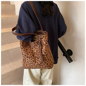 Close-up of leopard print tote bag with brown straps and gold logo on stairs