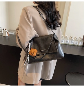 Détail du sac à épaule vintage en cuir noir avec chaîne métallique et pendentif chiot