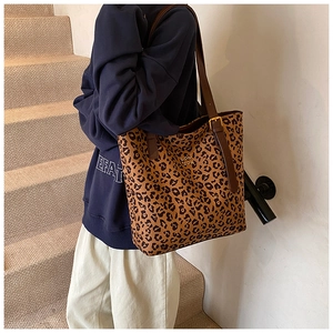 Detail of leopard print tote bag with brown leather strap and golden metal buckle