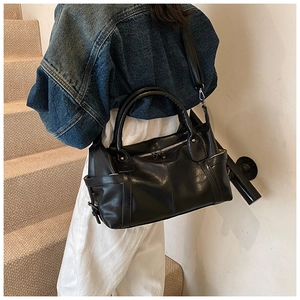 Detailed close-up of a black faux leather tote bag with silver zippers and stitching