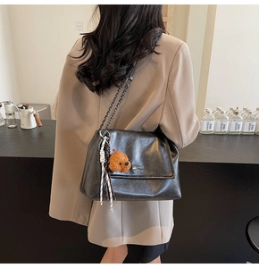Détail du sac à bandoulière en cuir noir souple avec chaîne et breloque peluche