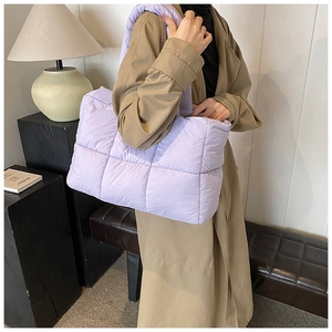 Detailed view of a light purple quilted puffer tote bag on a stylish geometric stand