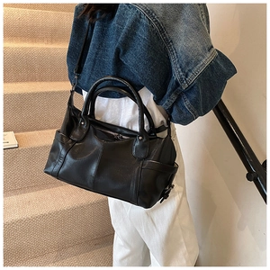 Detail view of the black tote bag with leather texture and detachable strap on stairs
