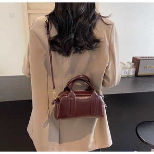 Details einer vintage weinroten Boston-Tasche mit Glanzleder und Goldbeschlägen