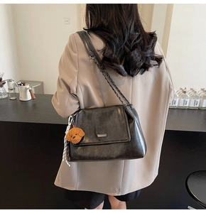 Détail du sac bandoulière en cuir noir avec breloque peluche chiot marron mignonne