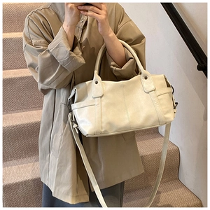 Close-up of beige Boston tote bag with dual handles and side pocket on a model