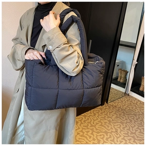Detail van de grote zwarte gewatteerde puffer tote tas met gevoerde handgrepen en rits