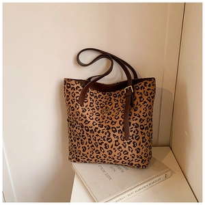 Close-up of leopard print tote bag featuring brown leather handles and gold buckle detail