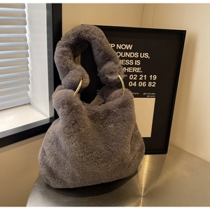 Détail du sac à main en fausse fourrure avec anneaux dorés et texture grise douce
