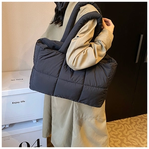Close-up of black puffer shoulder bag with quilted fabric and wide padded handle