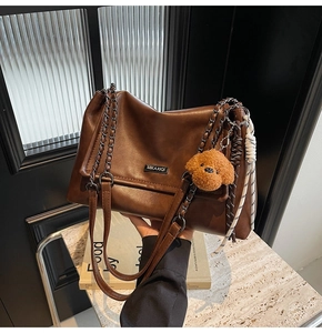 Gros plan sur le sac bandoulière rétro marron avec chaîne dorée et breloque caniche