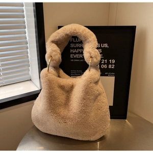Détails de la texture en fausse fourrure douce et anneaux dorés sur le sac en peluche beige
