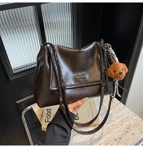 Vue détaillée du sac à bandoulière en cuir marron foncé avec chaîne et breloque ours