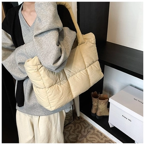 Detail of beige quilted puffer tote bag with wide shoulder strap for winter fashion
