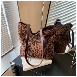 Detail of leopard print tote bag with brown faux leather handles on a vintage table