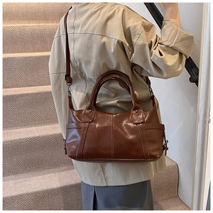 Deep brown retro tote bag shown in use with adjustable strap and textured leather finish