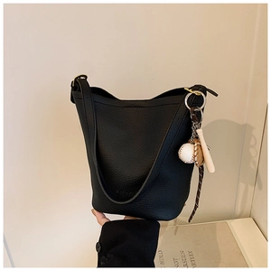Detail of black lychee grain leather bucket bag with a unique baseball theme charm